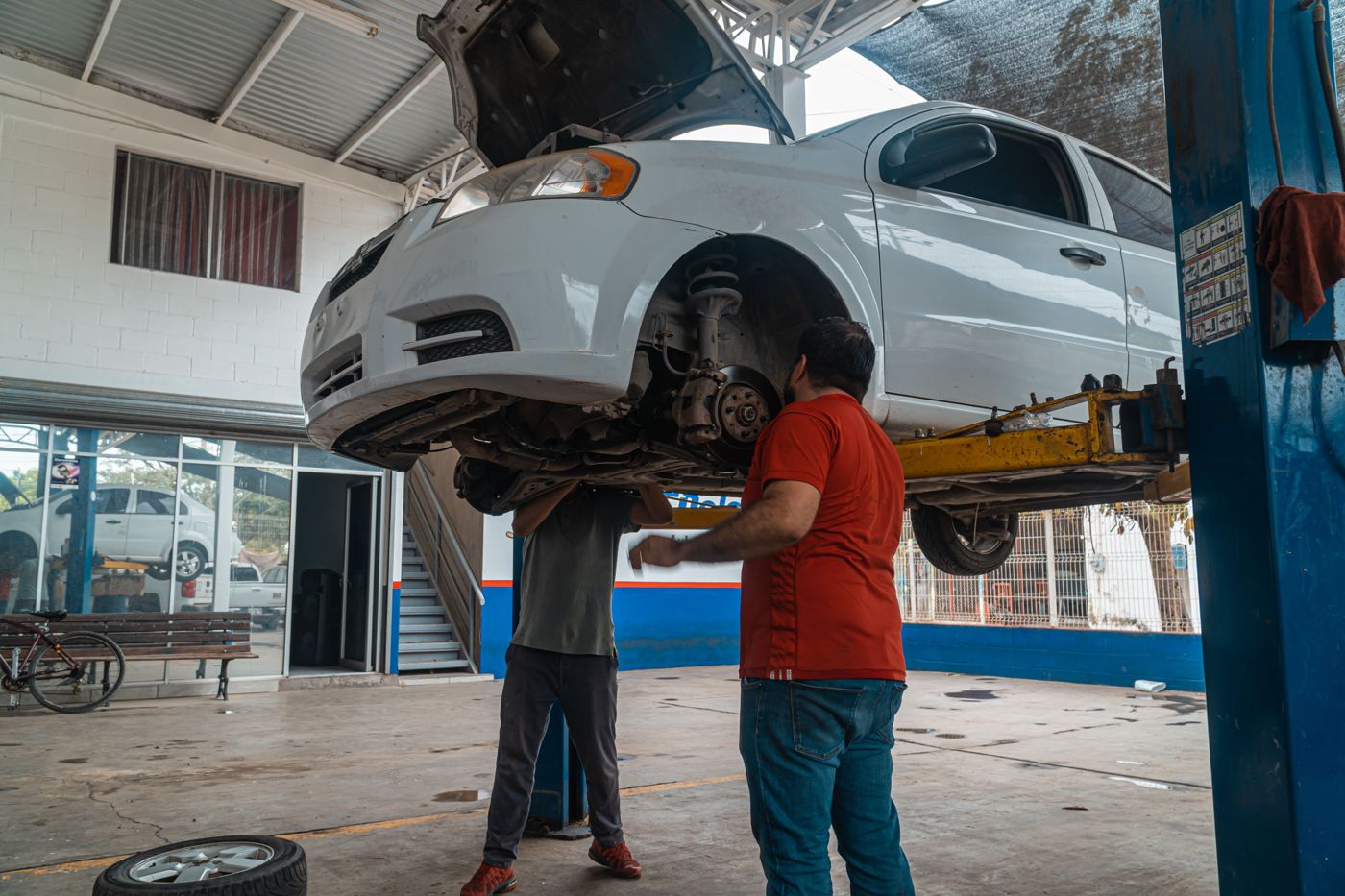 Dos mecánicos revisando un auto en un taller